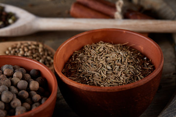 Various spices in wooden spoons and bowls and some salt on an old wooden barrel, top view, close-up, selective focus.