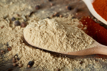 Top view of a wooden spoons full of paprica and black pepper on wooden barrel background, selective focus.