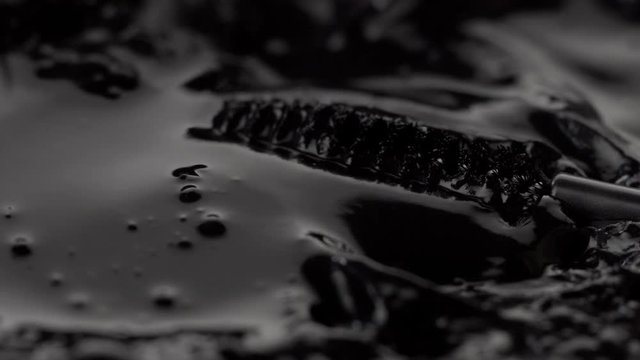 black liquid texture and mascara brush moving this liquid closeup cosmetics texture