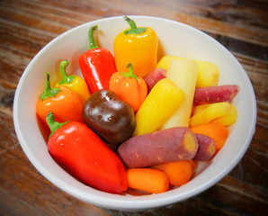 Bowl of washed and ready to eat fresh healthy colorful organic vegetables; sweet peppers and baby carrots in red, orange, yellow, purple and white color.