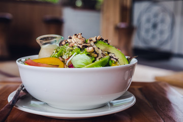 Green salad poke bowl with sesame dressing on a wooden table. Vegetarian raw meal concept