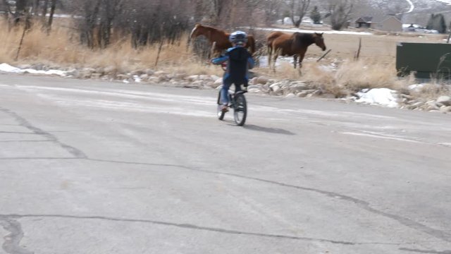 Slow motion of little boy riding a bike outside in the spring