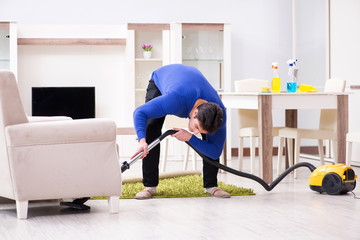 Young man vacuum cleaning his apartment