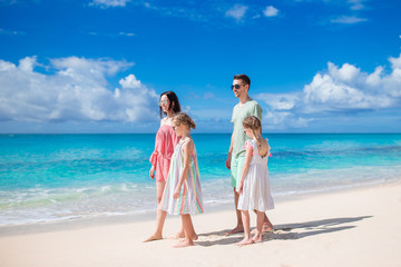 Family of four walking on white beach