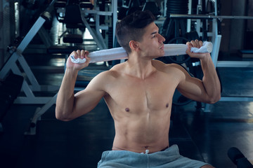 Fototapeta na wymiar Portrait of sport young fitness man with white towel on his neck, relax after exercise at indoor sport gym, healthy sport concept.