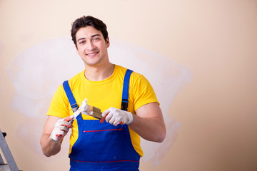 Young contractor employee applying plaster on wall
