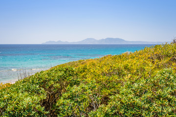 Beaches, Greece, Kos Island, Cap Helona: beautiful holiday setting on a secluded beach with umbrellas on the Greek Aegean Sea with turquoise waters and a picturesque bay and islands in the background