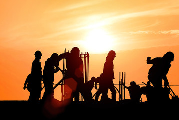 Labor Day Silhouette team of business engineers looking for blueprints on construction sites using unclear construction sites at sunset.