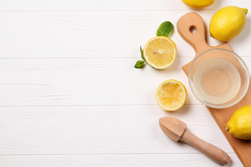 Lemon juice in a bowl on the table, a wooden juicer. Lemons