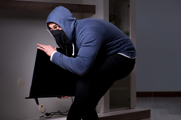 Burglar thief stealing tv from apartment house