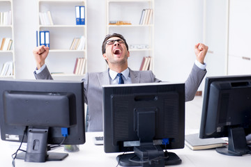 Businessman sitting in front of many screens