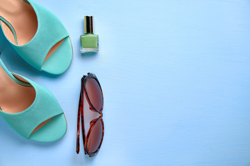 Summer concept, a set of womens shoes, nail polish, sunglasses on a blue background top view