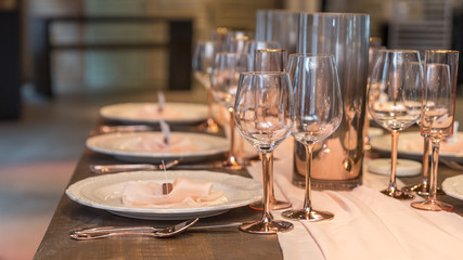 table set for banquet with silverware and glasses in red gold. Also a empty name tag set on center of plates