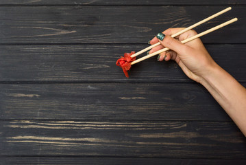 hand holds chopsticks with ginger
