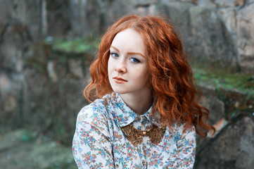 Portrait of a young red-haired curly girl with freckles in a vintage necklace