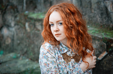 Portrait of a young red-haired curly girl with freckles in a vintage necklace