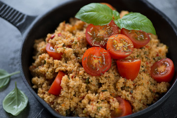 Close-up of couscous with cherry tomatoes and fresh green basil, selective focus
