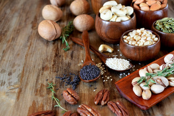 Different nuts and seeds in wooden spoons and bowls on a table