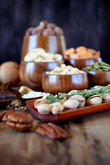 Different nuts and seeds in wooden spoons and bowls on a table