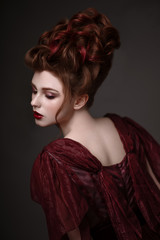 Portrait of redhead woman with baroque hairstyle and evening maroon dress