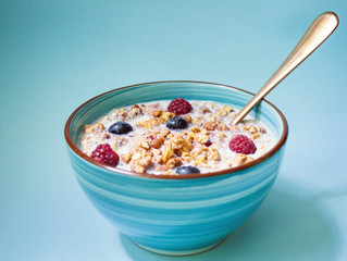 Bowl of healthy muesli for Breakfast with berries and milk, muesli, corn. On blue background