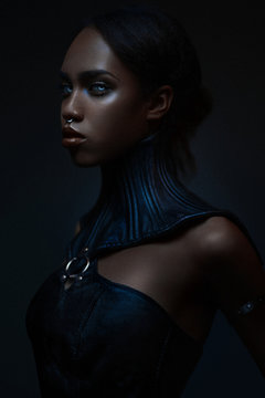 Portrait of black woman with gothic collar posing on dark background
