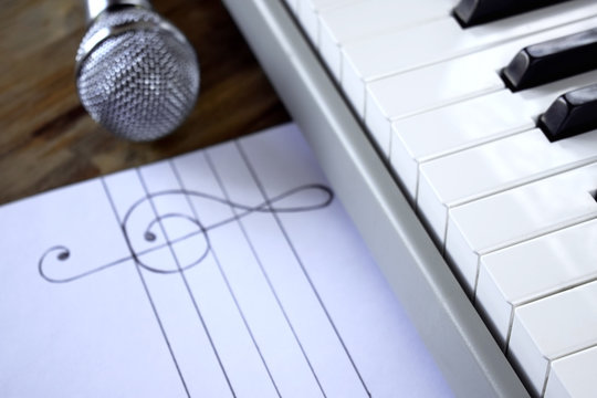 Synthesizer, microphone and treble clef on white paper