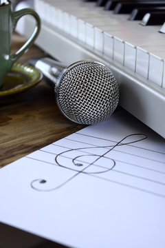 Synthesizer, microphone and treble clef on white paper