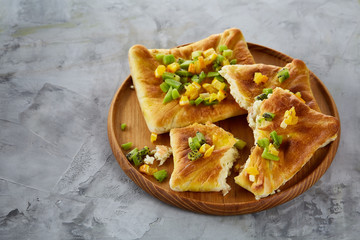 Delicious homemade fruit pies on wooden tray over light grey textured background, flat lay, close-up, selective focus
