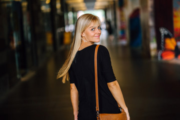 A charming blonde girl walking in the middle of the corridor and gracefully smiling to the camera....