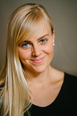 Naklejka premium Close-up profile portrait of a young and attractive blonde woman with blue eyes. She is smiling as she strikes a pose in front of the camera.