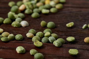 Green peas on rustic wooden background, close-up, top view, selective focus.