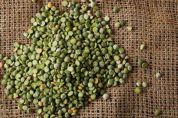 Pile of green peas on burlap tablecloth, close-up, top view, selective focus, shallow depth of...