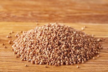 Buckwheat groats on wooden background, top view, close-up, selective focus.