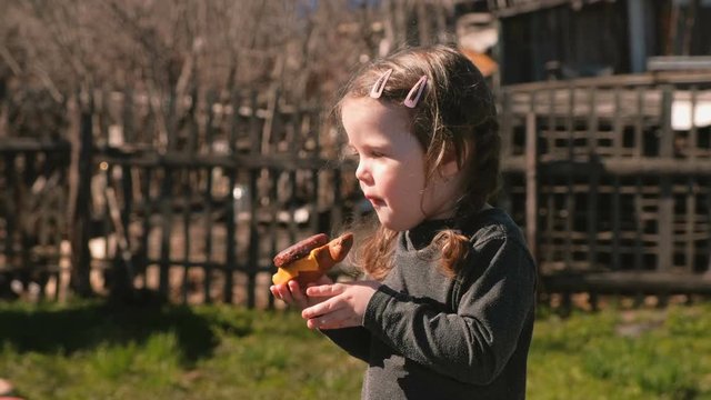 Young cute little girl eats a sandwich with cutlet and cheese.