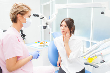 Young woman at the dentist complaining about a toothache. Dentistry. Doctor and the patient