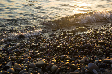 pebble stones on the sea beach, the rolling waves of the sea with foam