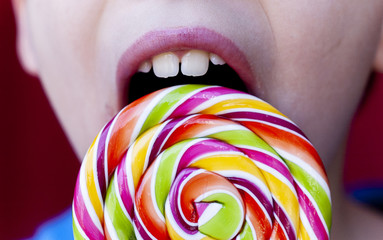 close up of the mouth of a kid lick a lollipop candy