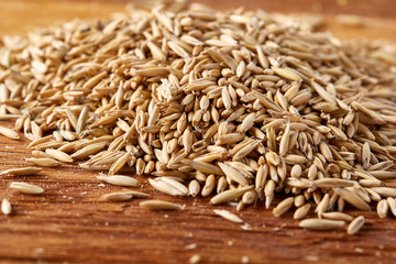 Obraz premium Pile of unpeeled oat grains on homespun tablecloth background, top view, close-up, macro, selective focus.