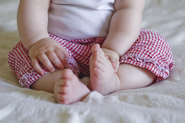 a small child sitting on a bed plays with his feet