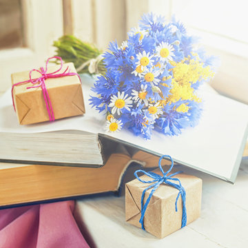 A bouquet of wild flowers, books and packed gifts on the windowsill.