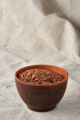 Bowl full of buckwheat grains on rustic wooden table, close-up, selective focus, shallow depth of field.