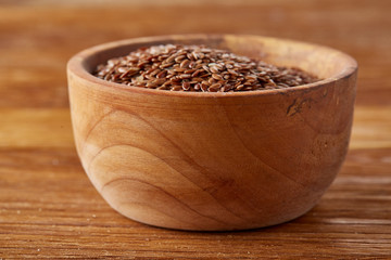 Bowl full of buckwheat grains on rustic wooden table, close-up, selective focus, shallow depth of field.