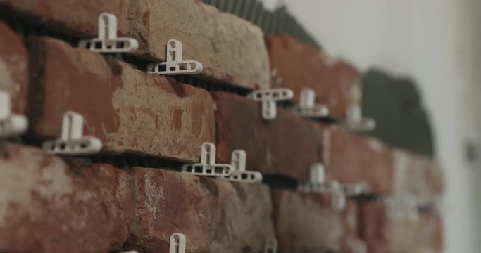 Slow motion closeup worker applying brick cuts tile to the wall