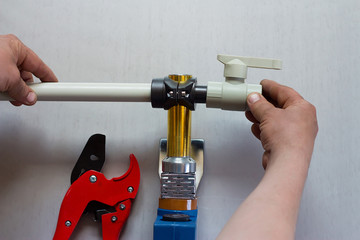 Soldering iron for polypropylene plumbing pipes. The hands of the plumber are holding the pipeline...