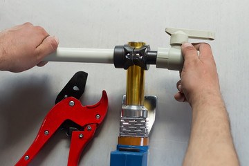 Soldering iron for polypropylene plumbing pipes. The hands of the plumber are holding the pipeline...