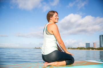 Fototapeta na wymiar Athletic young woman in SUP Yoga practice relaxing on her paddle board at Ala Moana Hawaii