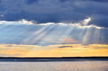 Sunset with sun rays shining through clouds.