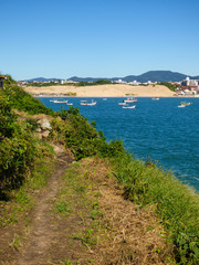 A view of Ingleses beach with boats in the ocean and sand dunes in the background (Florianopolis, Brazil)