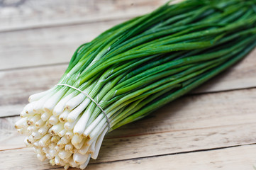 Fresh green onions on a light wooden table with texture.